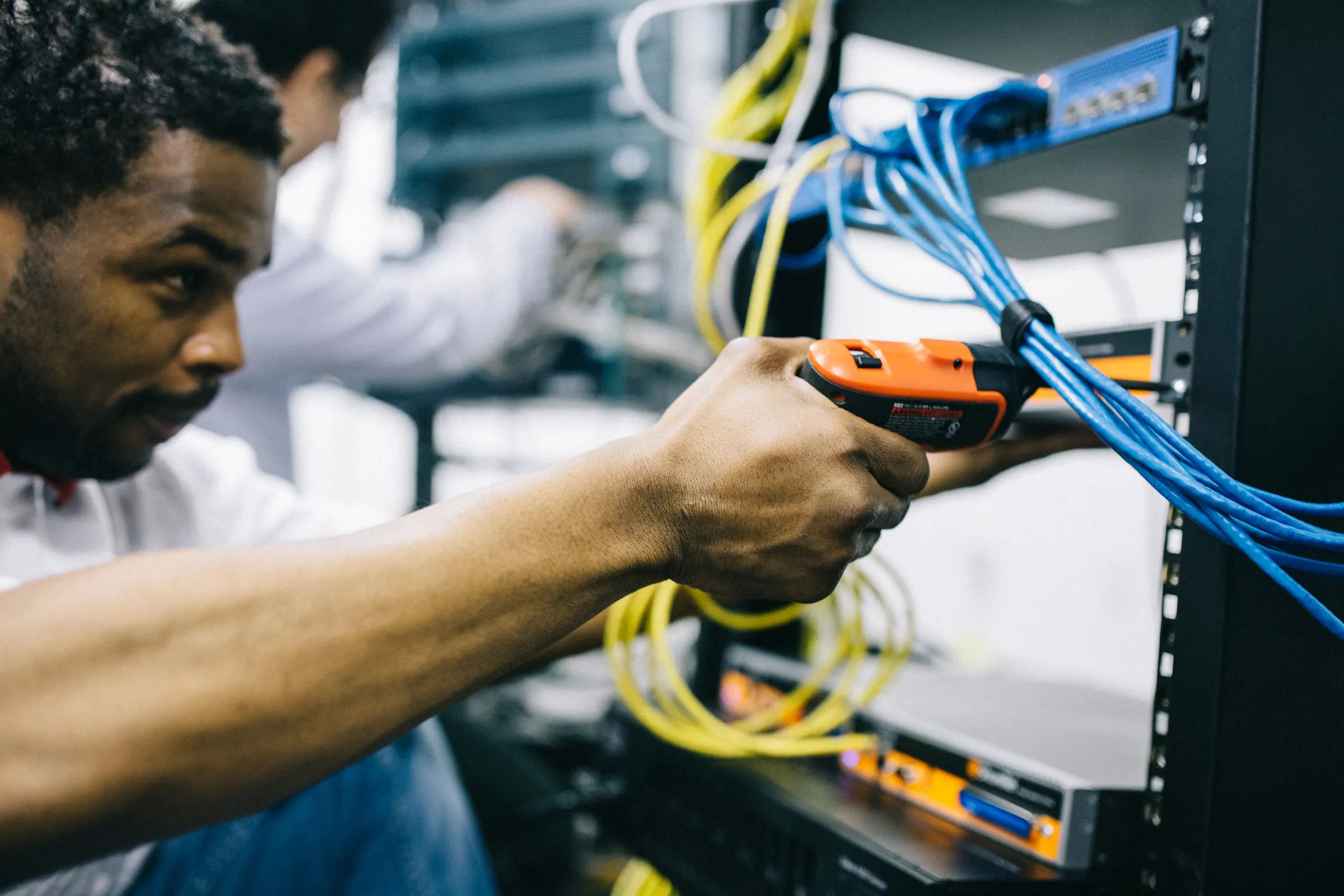Technician testing network cables at a server rack
