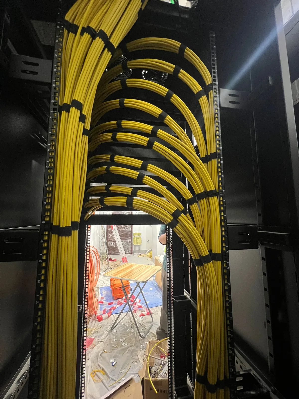 Fiber patch cords dressed in tidy loops down the side of a network rack