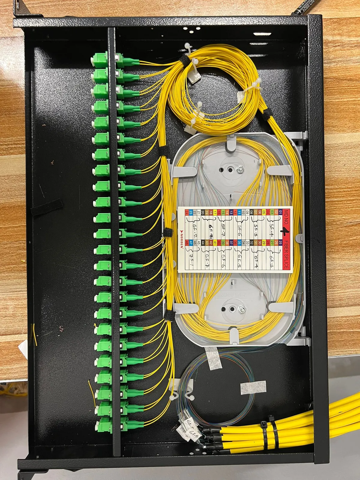 Fiber splice enclosure with green SC connectors, splice tray and labelled fiber map